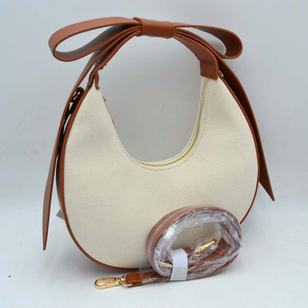 Brown Add a touch of feminine charm to your accessory collection with this striking crescent-shaped hobo bag. Blending the natural texture of a heavy-duty canvas body with an architectural, oversized bow handle, this statement handbag effortlessly bridges the gap between playful romance and contemporary high fashion. Whether worn as a chic top-handle bag or converted into a hands-free crossbody, its unique silhouette makes it a standout piece for any outfit.