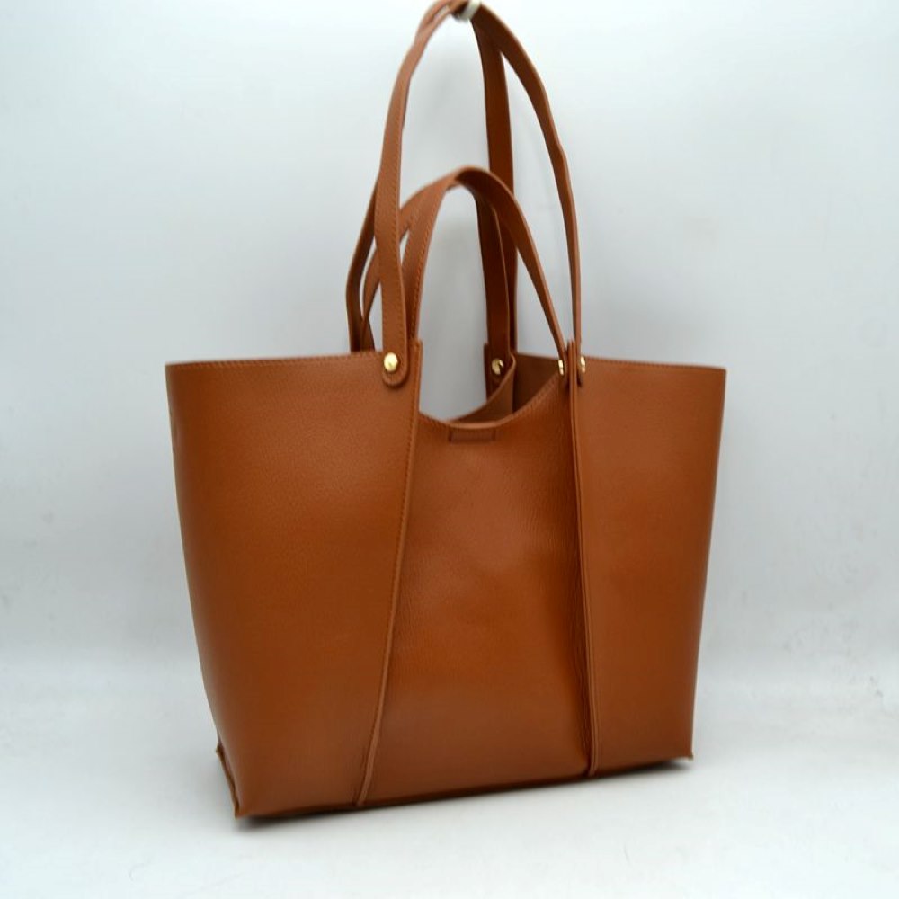 Brown This versatile tote bag is a sophisticated addition to any collection. Crafted from high-quality, durable material, it combines a structured, minimalist shape with a rich, tactile finish. Designed for the modern professional or frequent traveler, it features an elegant central panel design and is adorned with polished gold hardware studs that add a touch of understated luxury.