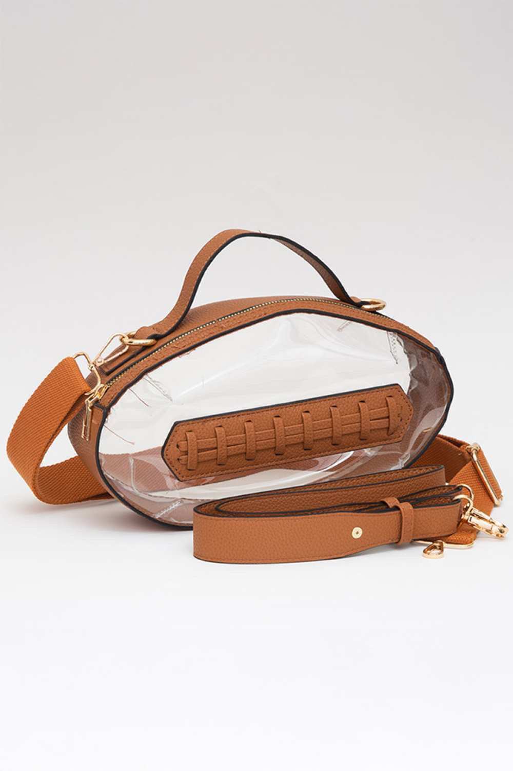Brown Carry your essentials in style with this unique football-shaped transparent crossbody bag. Perfect for stadium events, concerts, and outdoor gatherings, the clear PVC design lets you see everything inside while meeting venue security requirements. Measuring 11" x 6" x 4", it offers practical storage without bulk. The adjustable crossbody strap keeps your hands free, making it ideal for busy days out. Durable 100% PVC construction ensures long-lasting wear through countless adventures.