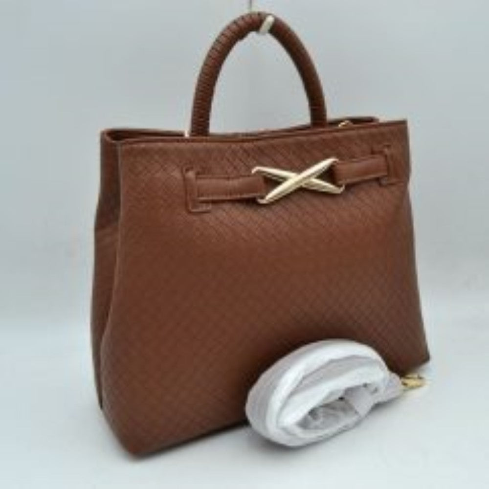 Brown This structured satchel features an intricately textured, woven pattern across the exterior, making it a sophisticated choice for elevated everyday use. The front panel is accented by a decorative horizontal band joined together with a prominent, metallic X-shaped hardware detail. Built with a sturdy, rounded top handle for a classic handheld carry, the bag also includes a main storage compartment and a detachable long shoulder strap secured by metallic clasps