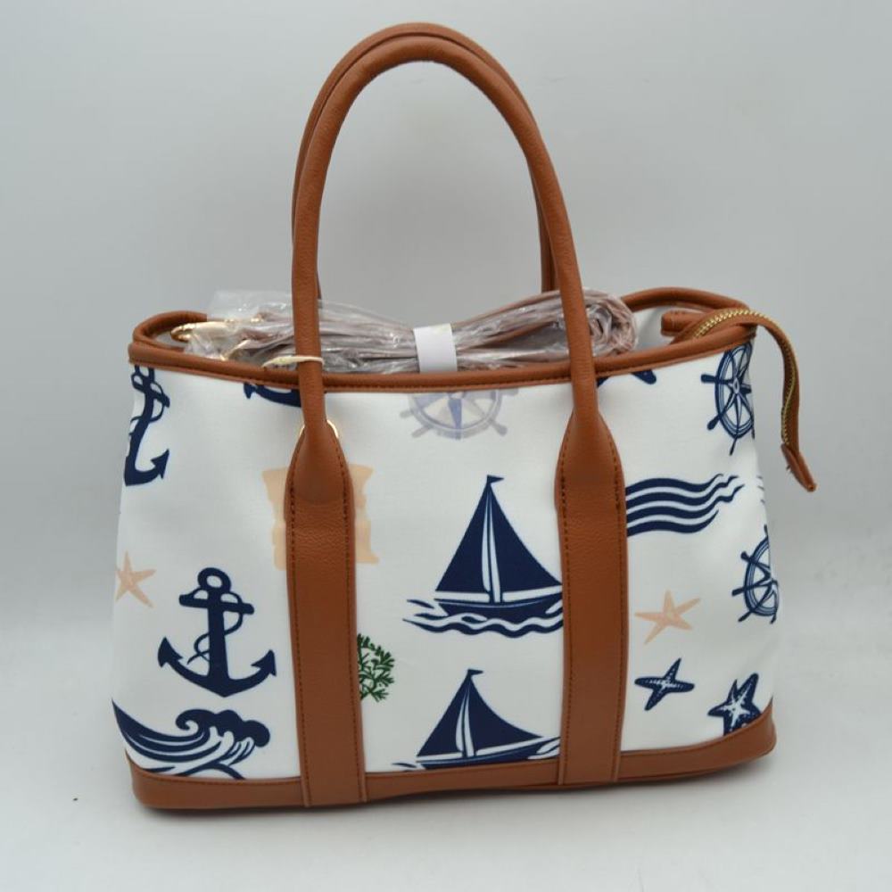 Brown Set sail with this nautical-inspired canvas tote. Featuring a crisp backdrop decorated with a classic print of anchors, sailboats, ship wheels, and ocean waves, this bag is the perfect accessory for coastal getaways or adding maritime flair to your daily ensemble. Framed with structured textured trim, it balances casual resort style with sharp, everyday functionality.