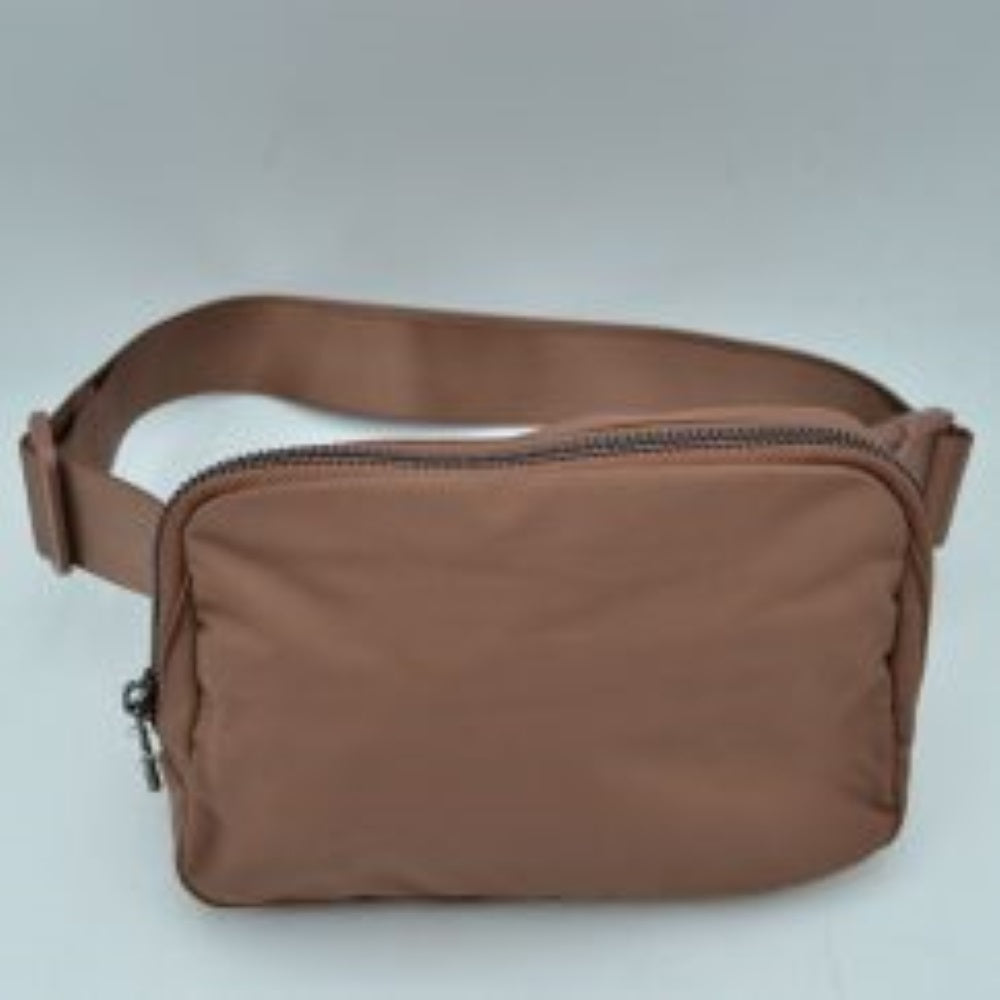 Brown This minimalist bag features a smooth, clean design ideal for versatile everyday use. The main storage compartment is secured by a curved top zipper with dual pulls for easy access to essentials. A wide, adjustable strap extends from the sides, complete with a matching slider to easily customize the fit for comfortable carrying.
