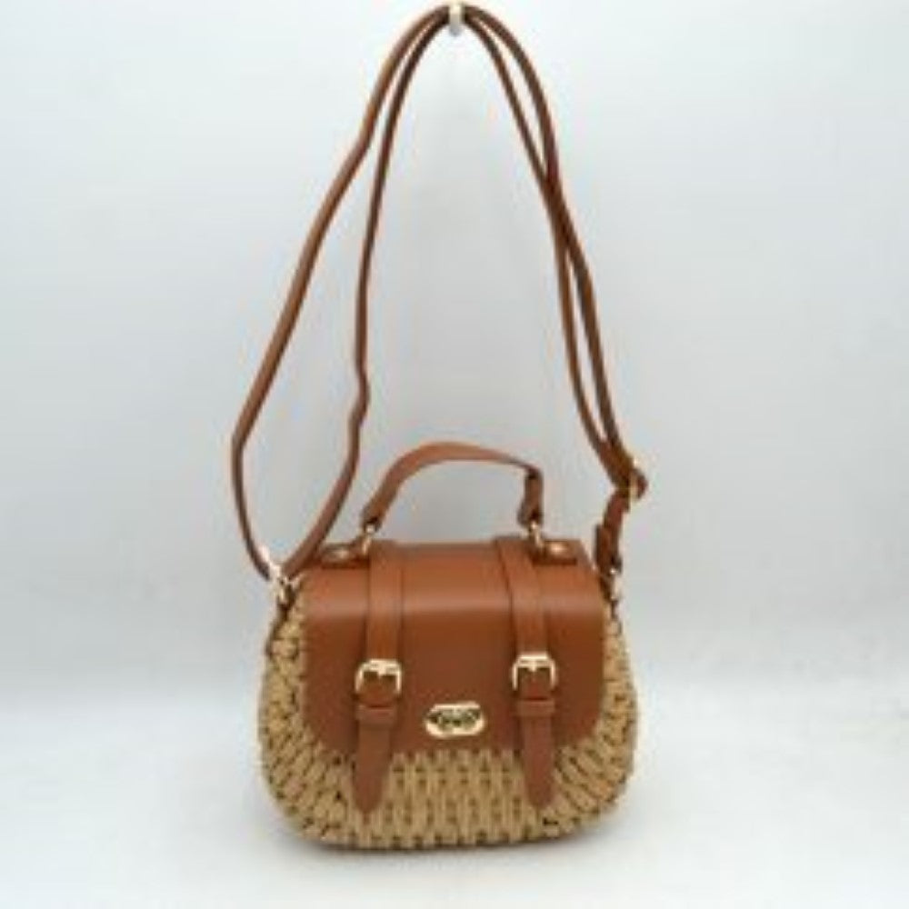 Brown This charming satchel features a woven straw body paired with a smooth faux leather foldover flap, making it a stylish choice for warm-weather outings. It is detailed with dual decorative buckle straps on the front along with a secure gold-tone turn-lock closure. Designed for versatile wear, it includes a sturdy top handle for handheld carrying and a long, adjustable shoulder strap for comfortable hands-free crossbody or shoulder styling.