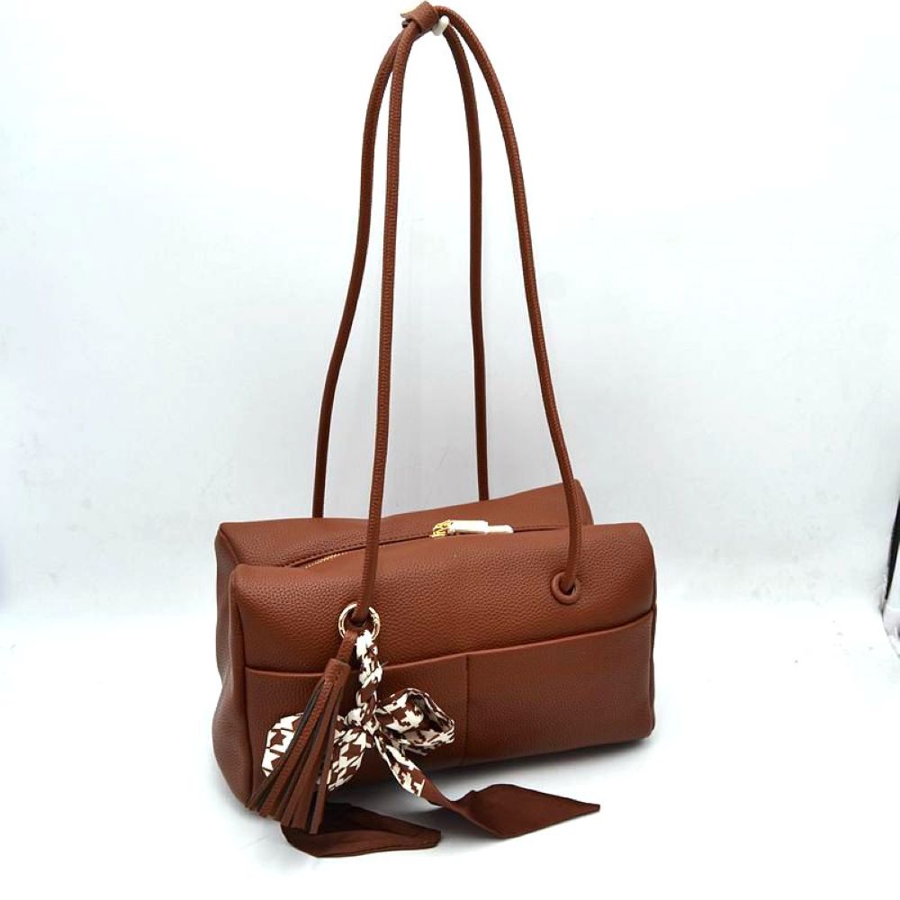 Brown This structural shoulder bag features a textured pebbled exterior in a warm brown tone, offering a contemporary barrel-shaped silhouette for stylish everyday use. Designed with functionality in mind, it features dual long, slim shoulder straps that loop through metallic grommets directly into the body panels. The spacious main compartment opens with a secure top zipper closure, while a matching leather tassel and a patterned houndstooth fabric scarf tied around the front handle base add a playful