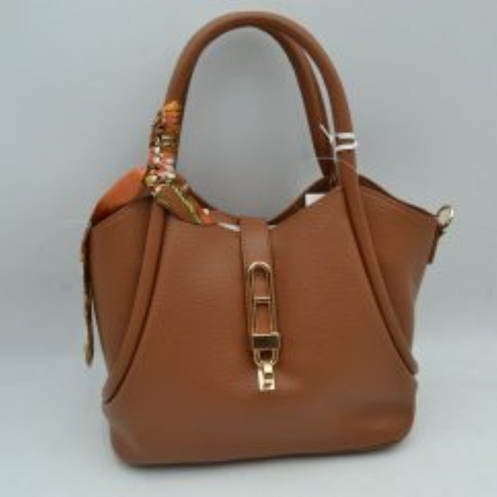 Brown This elegant everyday handbag features a textured pebbled body with a structured silhouette and a curved top opening. It offers versatile carrying options with its dual rounded top handles and a detachable, adjustable shoulder strap connected via gold-toned metal hardware. A central strap closure with a distinctive elongated metallic turn-lock clasp secures the main storage compartment