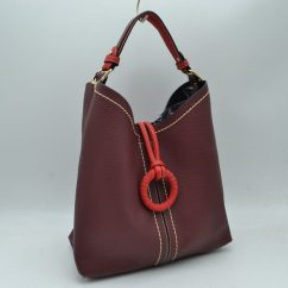 Burgunday This structured everyday bucket bag features a pebbled textured body with a distinctive curved, dip-top opening and prominent contrast stitching details along the front panel. It is designed with a singular flat top handle anchored to the sides by polished metal hardware loops for comfortable carrying. A central loop strap extends from the back to the front