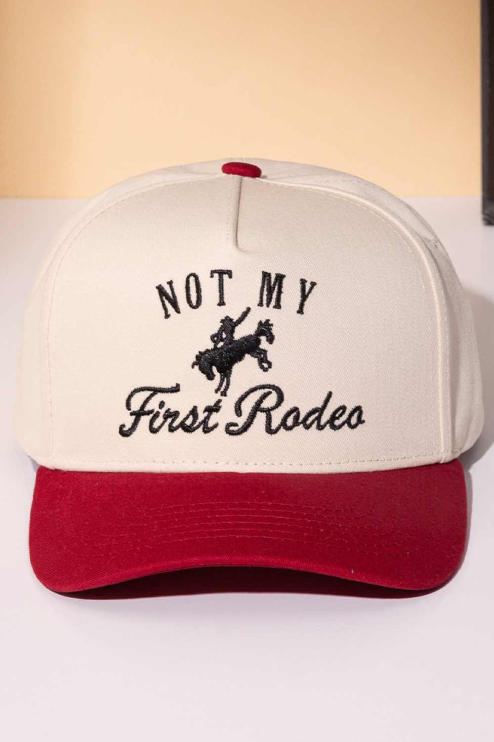 Burgundy Classic trucker cap with bold "NOT MY FIRST RODEO" embroidery across the front. Features a two-tone design that blends style with attitude. Crafted from 100% cotton for breathability and comfort. Snapback closure adjusts to fit most head sizes. Perfect for casual wear, outdoor adventures, or making a statement wherever you go.