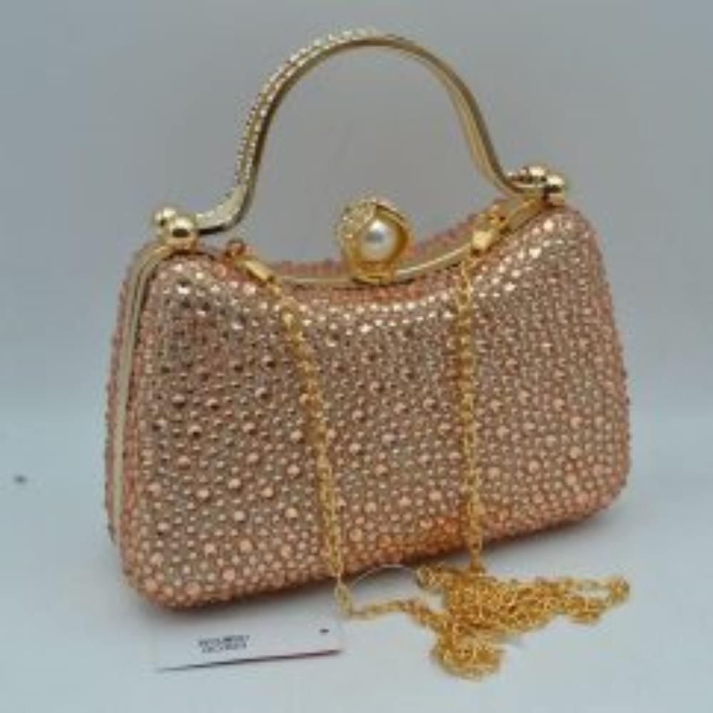 Champagne This elegant evening clutch bag features a structured silhouette heavily encrusted with shimmering black rhinestones, offering a highly textured and glamorous look for formal events. A sleek, curved metallic top handle lined with delicate crystals rises over the frame for a secure grip, anchored by polished spherical accents. The secure metal frame is highlighted by a prominent decorative clasp featuring a large faux pearl wrapped in rhinestone-studded detailing
