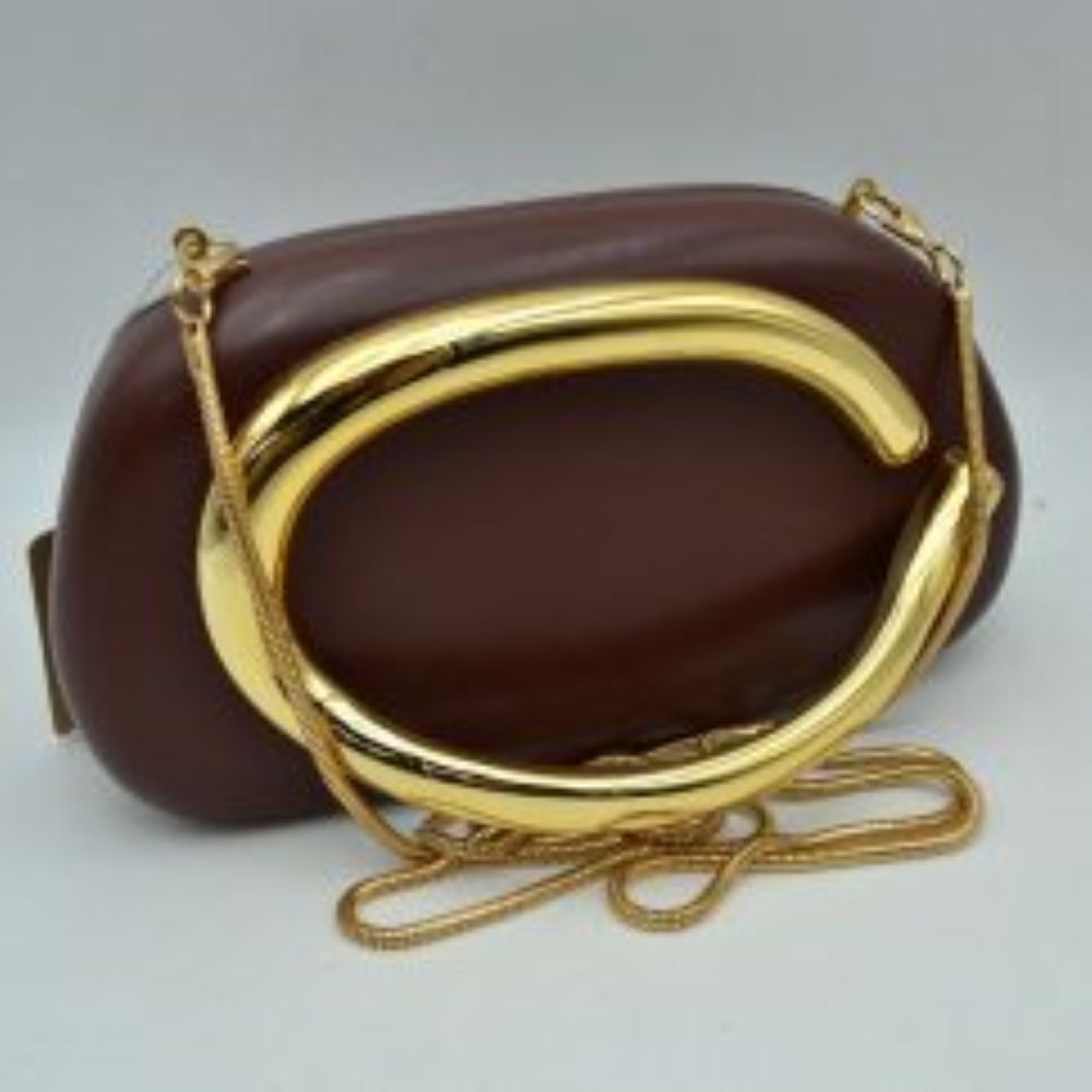 Coffee This structured, hard shell clutch bag functions as an elegant accessory for everyday use or special occasions, featuring a smooth matte surface. A large, prominent metallic ring handle anchors the front design, offering a secure hand-held grip. For alternative carrying styles, the bag is equipped with a detachable metallic snake chain strap that secures to the top corners with lobster claw clasps, providing functional storage in a compact, rigid silhouette.