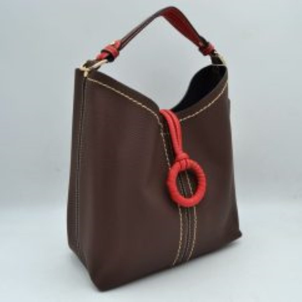 Coffee This structured everyday bucket bag features a pebbled textured body with a distinctive curved, dip-top opening and prominent contrast stitching details along the front panel. It is designed with a singular flat top handle anchored to the sides by polished metal hardware loops for comfortable carrying. A central loop strap extends from the back to the front