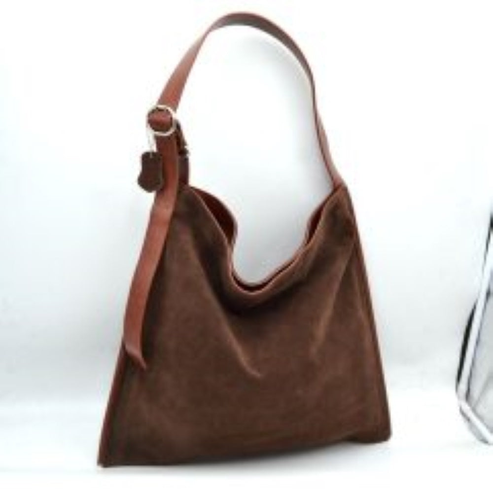 Coffee This slouchy hobo bag features a clean, soft-textured exterior with a relaxed, square-shaped silhouette that makes it ideal for everyday use. Designed with a spacious main compartment to easily organize and store daily essentials, the bag is equipped with a wide, flat shoulder strap for comfortable carrying. The single strap includes a metallic buckle closure system on one side, allowing for functional adjustments while adding a touch of classic detail to the overall minimalist design.