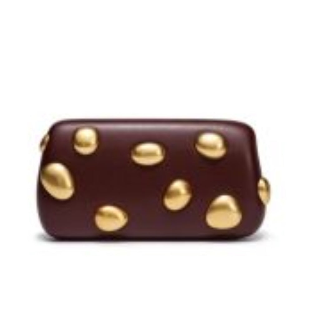 Coffee This structured clutch bag features an elongated, smooth silhouette with softly rounded corners, making it a distinctive accessory for everyday styling. The exterior design is adorned with scattered, three-dimensional metallic embellishments shaped like organic pebbles that add a bold, tactile element to the smooth surface. Crafted as a sleek, strapless handheld piece, it encloses a single internal storage compartment with a seamless top closure for a clean and minimalist presentation.