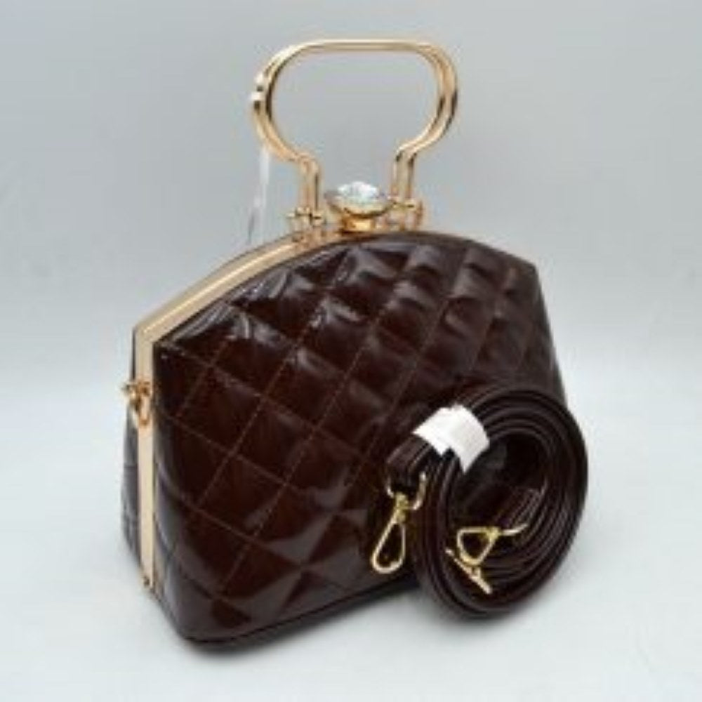 Coffee This structured handbag features a glossy, quilted exterior pattern that adds texturing to its rigid silhouette for everyday use. It is styled with distinctive metallic top handles and a secure upper storage compartment accessible through a solid frame opening. An ornamental crystal-like clasp sits prominently at the top closure, while side hardware rings accommodate the included matching detachable shoulder strap with metallic clips for multi-way wear.