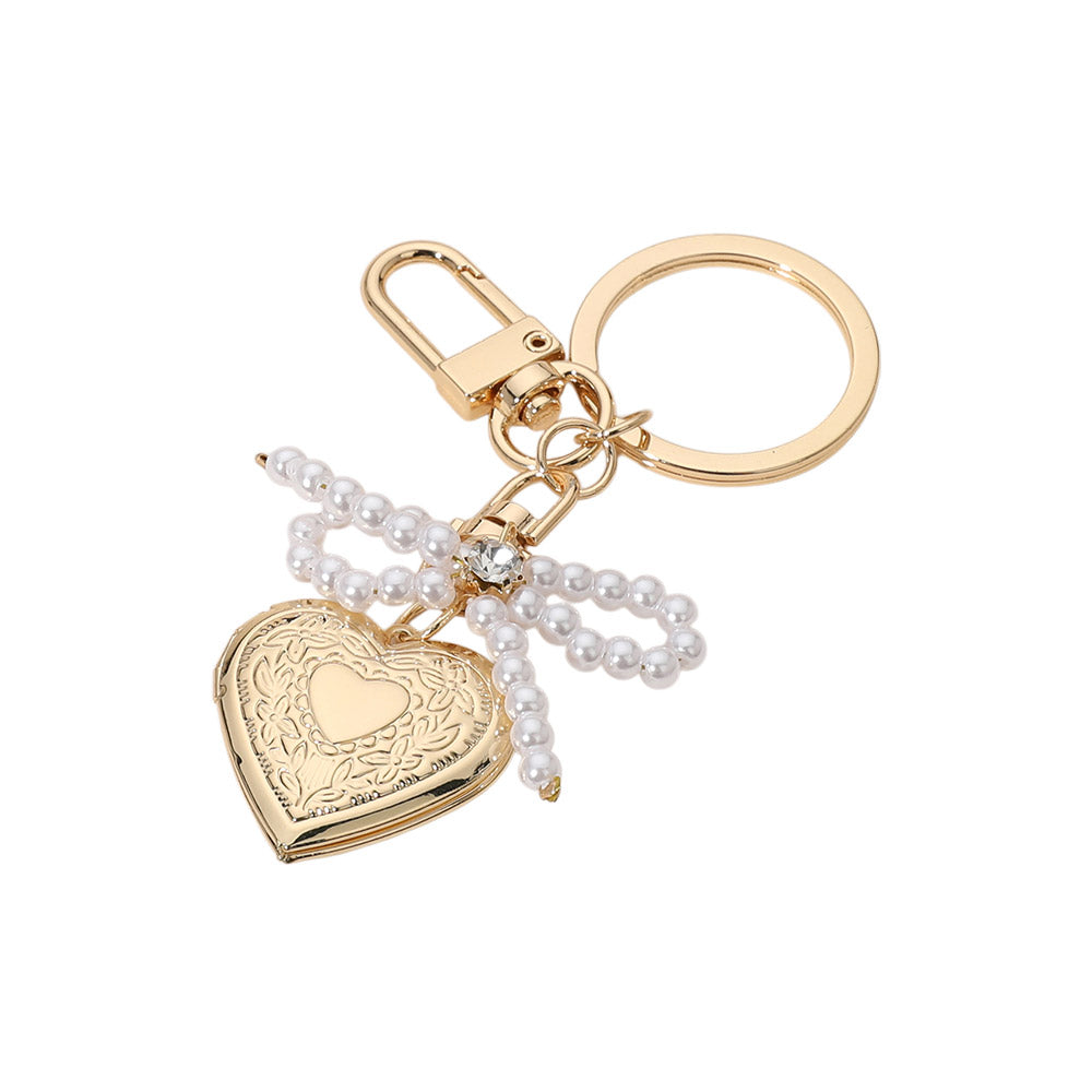 Cream Gold Pearl Beaded Bow Pointe Metal Heart Locket Bag Charm adds a touch of elegance to any bag. The pearl beads and metal heart locket create a stunning, timeless look. Perfect for adding a subtle pop of glamour to your everyday bag.