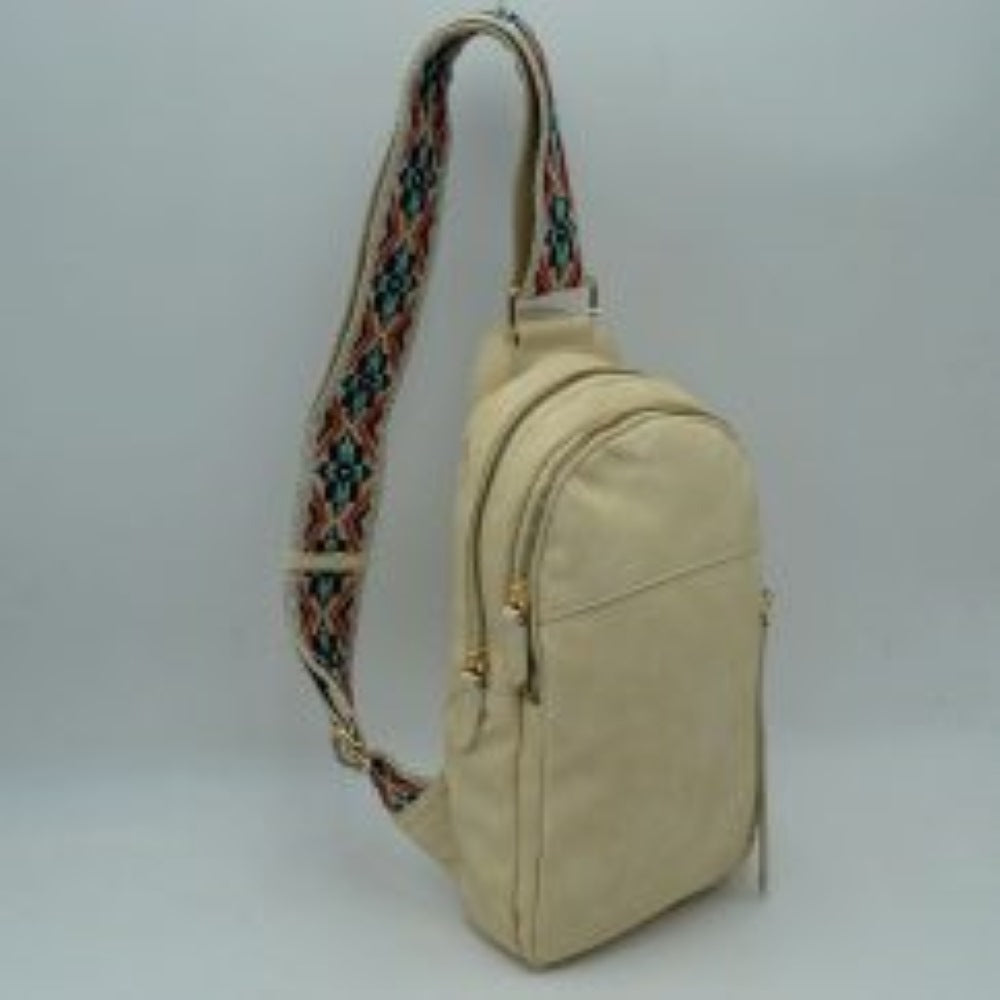 Cream This multi-compartment sling backpack features a smooth texture and a contoured, upright silhouette optimized for daily use. It offers practical storage compartments, consisting of two tiered main sections with independent gold-tone zipper closures alongside a side-access vertical zippered pocket. A distinctive, wide fabric shoulder strap decorated with a detailed geometric woven pattern connects securely to the top and bottom anchors