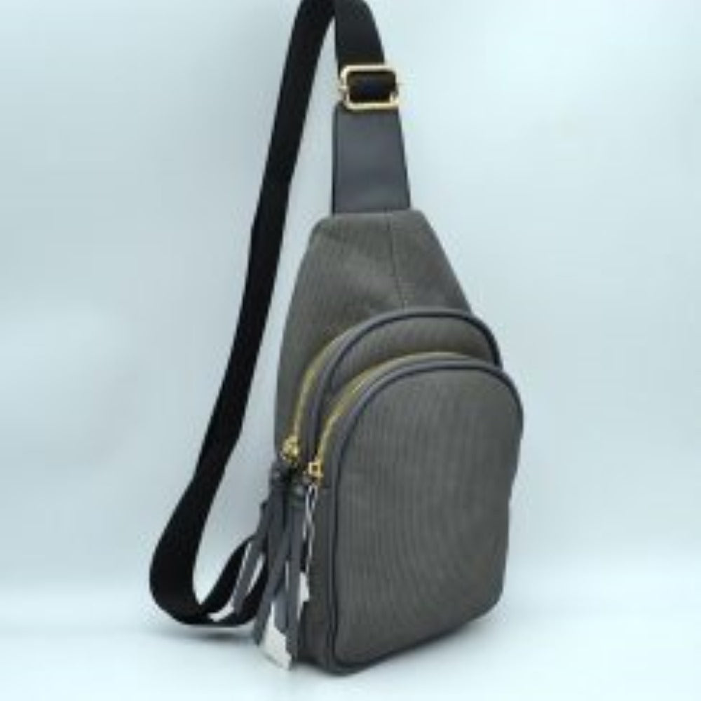 Dark-gray This practical sling bag features a textured, finely ribbed exterior w/ a tapered silhouette designed for comfortable everyday use. It offers organized storage compartments, including a curved main zippered section and a matching smaller front zippered pouch, both enhanced by elongated vertical tassel pulls hanging from the sliders. The bag is equipped w/ a single wide fabric shoulder strap attached to a smooth top panel & secured w/ a metallic adjustment buckle to easily customize the carrying 