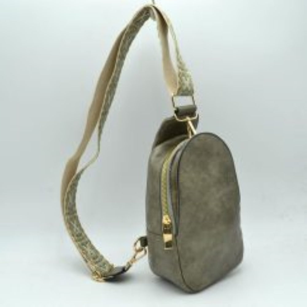 Dark-Gray This compact sling backpack features a smooth textured finish and a contoured, teardrop-shaped silhouette designed for casual everyday use. It includes a primary storage compartment that secures with a prominent gold-tone zipper and a flat pull tab for easy access to essentials. A distinctive, wide shoulder strap decorated with an intricate geometric pattern connects via gold-tone metal clips to various anchor loops, allowing for adjustable and versatile cross-body or over-the-shoulder wear.