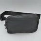 Dark gray This minimalist bag features a smooth, clean design ideal for versatile everyday use. The main storage compartment is secured by a curved top zipper with dual pulls for easy access to essentials. A wide, adjustable strap extends from the sides, complete with a matching slider to easily customize the fit for comfortable carrying.