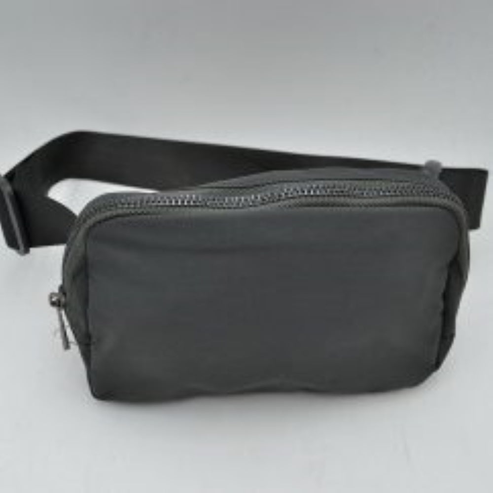 Dark gray This minimalist bag features a smooth, clean design ideal for versatile everyday use. The main storage compartment is secured by a curved top zipper with dual pulls for easy access to essentials. A wide, adjustable strap extends from the sides, complete with a matching slider to easily customize the fit for comfortable carrying.