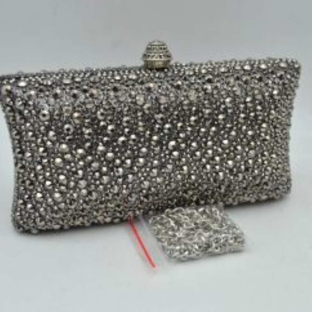 Dark-Silver This elegant box clutch bag features an all-over array of faceted, shimmering rhinestone embellishments that fully cover the exterior for a textured, light-catching look. Designed for evening or special occasion use, the structured frame includes a secure top clasp closure with a tiered, decorative knob that easily snaps open to access the main storage compartment. A matching, detachable metallic link chain strap with a secure lobster clasp is included