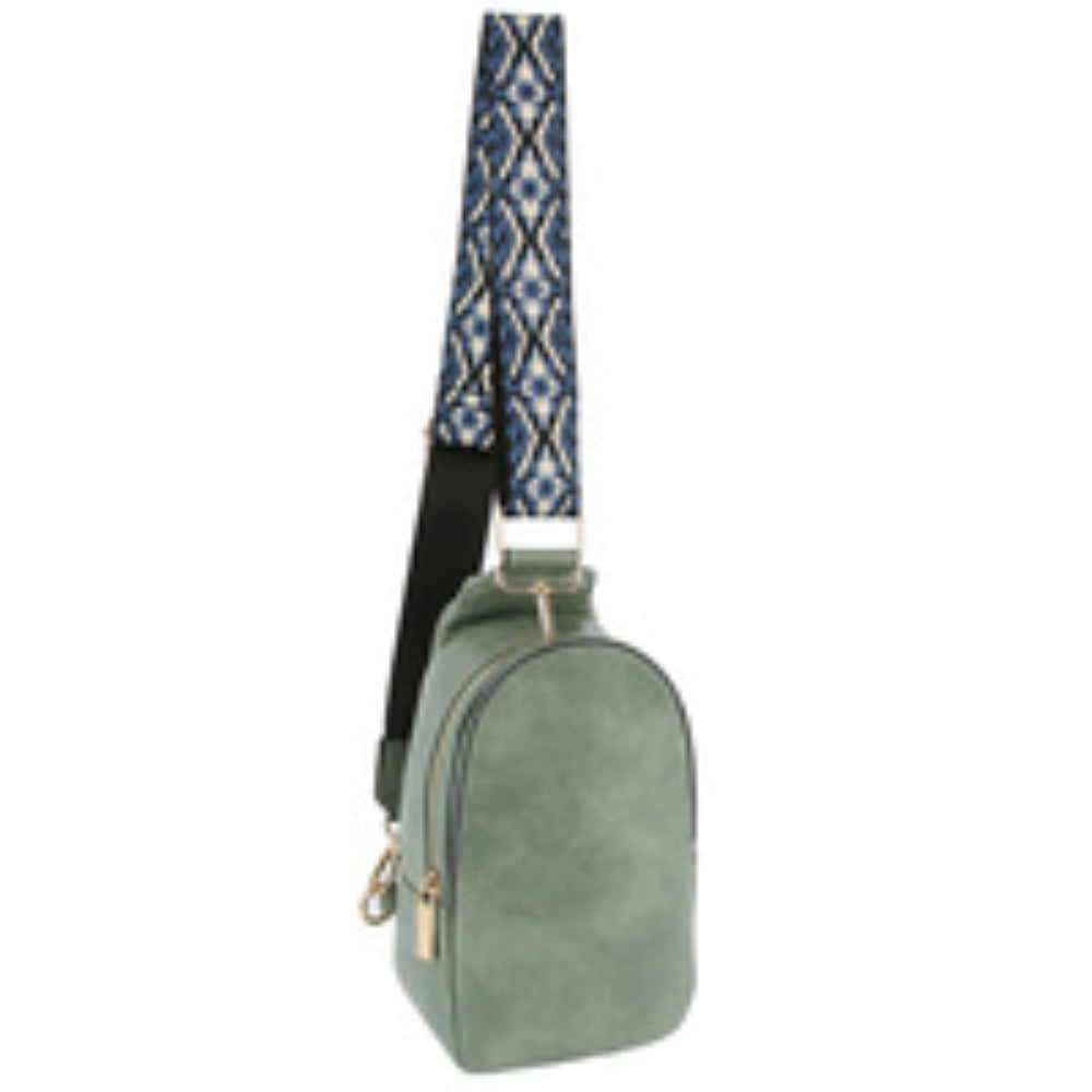 Denim This compact sling backpack features a smooth textured finish and a contoured, teardrop-shaped silhouette designed for casual everyday use. It includes a primary storage compartment that secures with a prominent gold-tone zipper and a flat pull tab for easy access to essentials. A distinctive, wide shoulder strap decorated with an intricate geometric pattern connects via gold-tone metal clips to various anchor loops, allowing for adjustable and versatile cross-body or over-the-shoulder wear.