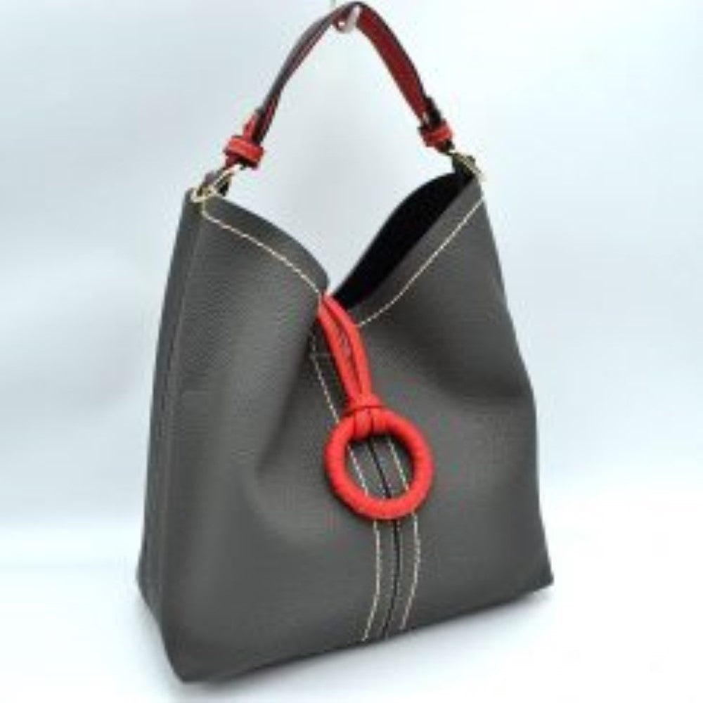 Dust Gray This structured everyday bucket bag features a pebbled textured body with a distinctive curved, dip-top opening and prominent contrast stitching details along the front panel. It is designed with a singular flat top handle anchored to the sides by polished metal hardware loops for comfortable carrying. A central loop strap extends from the back to the front

