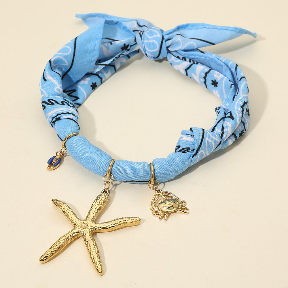 Madeline Love Blue, Gold Textured Metal Starfish Conch Shell Crab Charm Nautical Print Fabric Wrap Statement Necklace - Necklaces