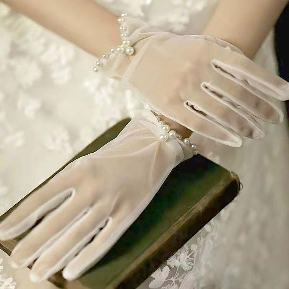 White Sheer gloves featuring a delicate pearl accent around the wrist. Ideal for weddings, formal occasions, or vintage-inspired looks. These gloves bring an elegant and refined touch to any special event outfit.