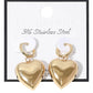 Gold SECRET BOX Stainless Steel Heart Dangle Huggie Hoop Earrings are expertly crafted with high-quality stainless steel for durability and long-lasting wear. The elegant heart dangle adds a touch of romance, while the secure huggie hoop design ensures comfortable and easy wear. Elevate any outfit with these stylish and timeless earrings.