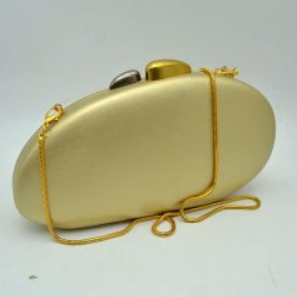 Gold This structured hardcase clutch bag features a smooth, rounded oval silhouette designed as a sleek accessory for everyday use. Its single interior storage compartment is secured with a rigid frame closure, accented at the top by a distinctive, asymmetrical two-tone sculptural clasp. A slender, matching metallic snake chain strap connects to small loop anchors on either side via clasp attachments, offering convenient options for hands-free shoulder or crossbody styling.