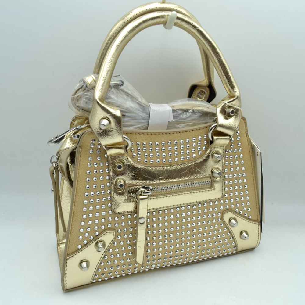 Gold This striking satchel bag features an elaborate array of rounded studs arrayed across the front panel, complemented by metallic corner patches and decorative rivets. Perfect for bringing a touch of bold style to everyday wear, it is designed with dual structured top handles for comfortable handheld carrying and features a front zippered storage compartment with a matching pull tab for easy access to smaller items. A secure main zippered closure ensures your daily essentials are protected
