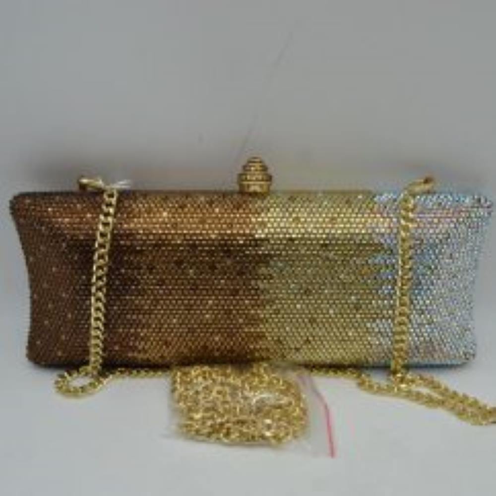Gold-Multi This structured clutch bag features an elongated silhouette with subtly flared edges, completely covered in fine, glittering micro-embellishments that create a shimmering, textured surface suitable for elegant everyday use. The central storage compartment is securely accessed via a hard-frame opening with an ornamental, rounded top clasp. A long, slender metallic curb chain strap is permanently attached to the top loops