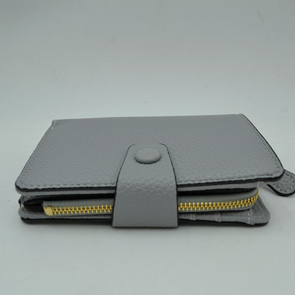 Gray This compact everyday wallet features a distinct pebbled texture and neat border stitching for a clean, structured appearance. Designed for efficient organization, the multi-compartment layout includes an accessible side storage compartment with a metallic zipper alongside a fold-over section secured by a central strap and snap-button closure. Its streamlined profile easily slips into larger bags or can be carried independently