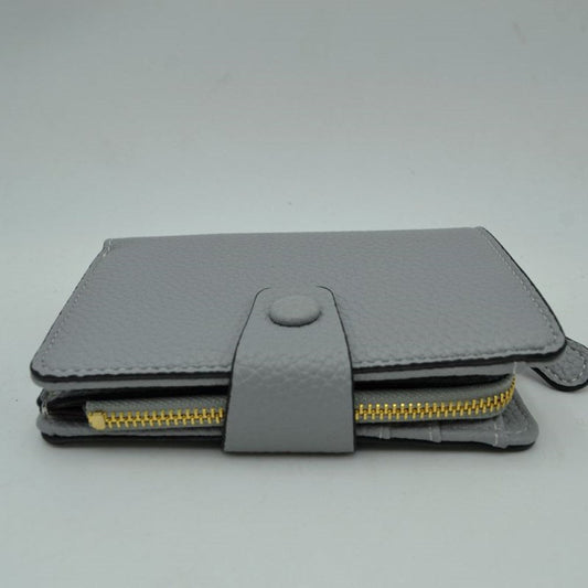 Gray This compact everyday wallet features a distinct pebbled texture and neat border stitching for a clean, structured appearance. Designed for efficient organization, the multi-compartment layout includes an accessible side storage compartment with a metallic zipper alongside a fold-over section secured by a central strap and snap-button closure. Its streamlined profile easily slips into larger bags or can be carried independently