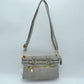 Gray This functional crossbody bag is designed for organized everyday use, featuring a textured exterior equipped with multiple secure storage compartments. The front panel includes a convenient horizontal zippered pocket accented with an oversized metallic zipper pull, situated beneath a decorative horizontal band detailed with metallic studs and loops.