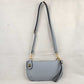 Gray This versatile everyday bag features a compact pebbled textured body with a slightly curved base silhouette. Designed for organized daily or evening use, the main storage compartment is secured by a top zipper closure and accented with a small decorative metallic turn-lock detail on the side panel. It offers multiple carrying options, equipped with a long, adjustable crossbody shoulder strap and a shorter matching wristlet loop