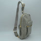 Gray This functional sling bag features a textured, grained finish exterior designed for streamlined everyday use. It offers multiple practical storage compartments, including a curved main section secured by a prominent metallic zipper track and a secondary front pocket with a horizontal zipper and an elongated pull tab. The bag is equipped with a single wide shoulder strap that attaches via a rectangular loop and incorporates an adjustable metallic buckle to easily customize the carrying length.