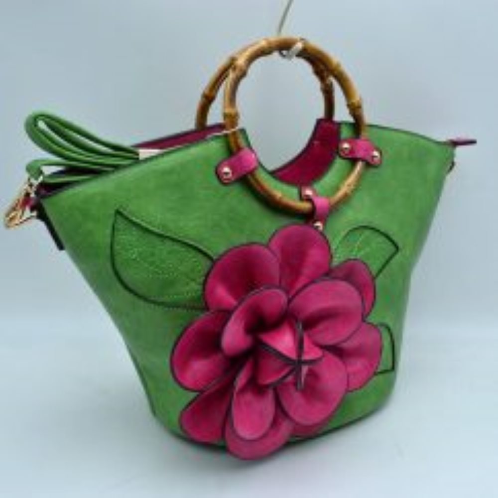 Green This structural tote bag is designed for standout everyday use, showcasing a prominent three-dimensional floral applique paired with stitched leaf accents on the front panel. It features segmented, circular top handles secured to the curved upper rim with studded contrasting tabs. The main storage compartment opens widely at the top to reveal a vibrant interior lining
