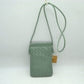Green This compact vertical crossbody bag is designed for everyday functionality with a distinct woven textured pattern across its body. It features a slim, continuous cord strap attached securely to the sides with visible knot details for comfortable carrying. A clean horizontal opening at the top allows effortless access to the main storage compartment