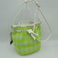 Green This everyday bucket bag features a distinctive argyle diamond pattern across its structured main body. Ideal for daily use, it is designed with a long, adjustable shoulder strap connected via metallic side rings. The spacious main storage compartment features an open-top design that closes with a functional drawstring woven through integrated metallic grommets along the upper rim, securing at the front with a knotted tie accent.