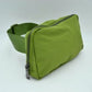 Green This minimalist bag features a smooth, clean design ideal for versatile everyday use. The main storage compartment is secured by a curved top zipper with dual pulls for easy access to essentials. A wide, adjustable strap extends from the sides, complete with a matching slider to easily customize the fit for comfortable carrying.