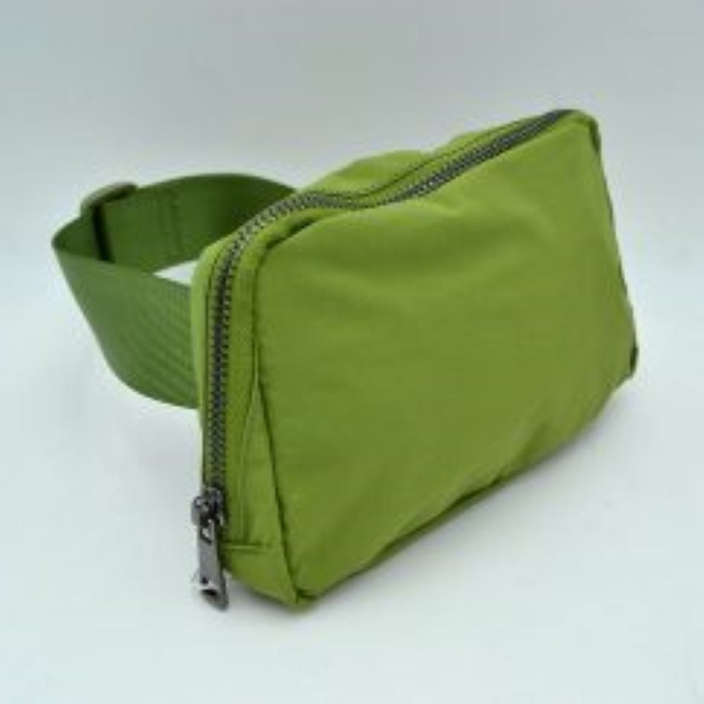 Green This minimalist bag features a smooth, clean design ideal for versatile everyday use. The main storage compartment is secured by a curved top zipper with dual pulls for easy access to essentials. A wide, adjustable strap extends from the sides, complete with a matching slider to easily customize the fit for comfortable carrying.