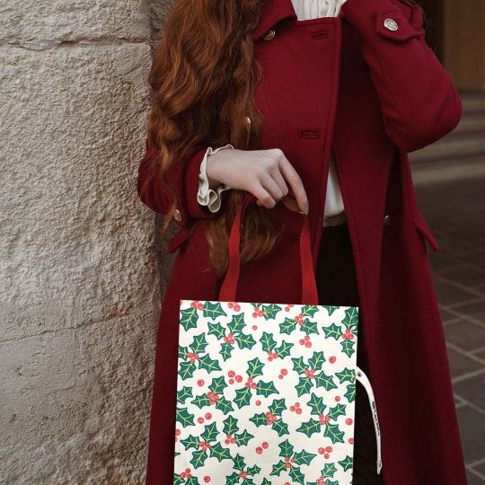 Reusable Christmas tote bag featuring a festive holly and berry print. Ideal for holiday shopping, gifting, or seasonal outings. Durable and stylish, it's a cheerful addition to your holiday essentials.