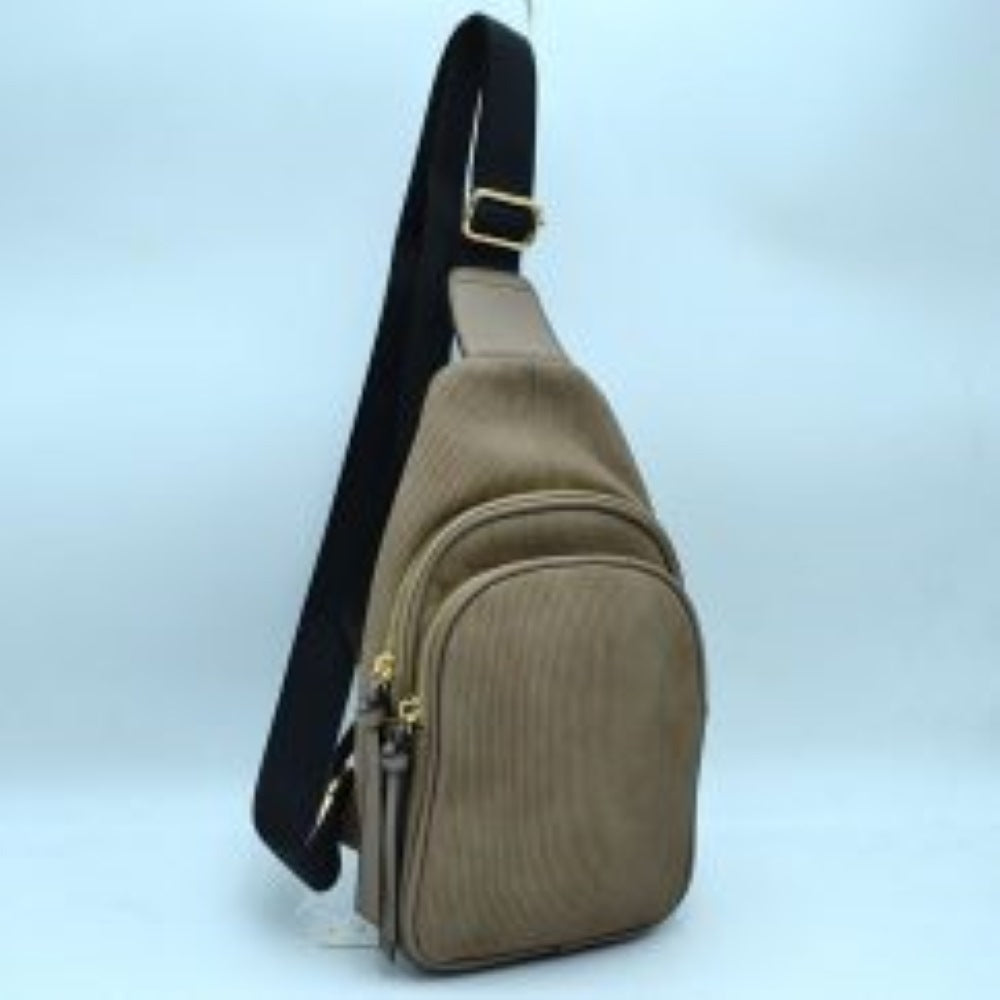 Khaki This practical sling bag features a textured, finely ribbed exterior w/ a tapered silhouette designed for comfortable everyday use. It offers organized storage compartments, including a curved main zippered section and a matching smaller front zippered pouch, both enhanced by elongated vertical tassel pulls hanging from the sliders. The bag is equipped w/ a single wide fabric shoulder strap attached to a smooth top panel & secured w/ a metallic adjustment buckle to easily customize the carrying length