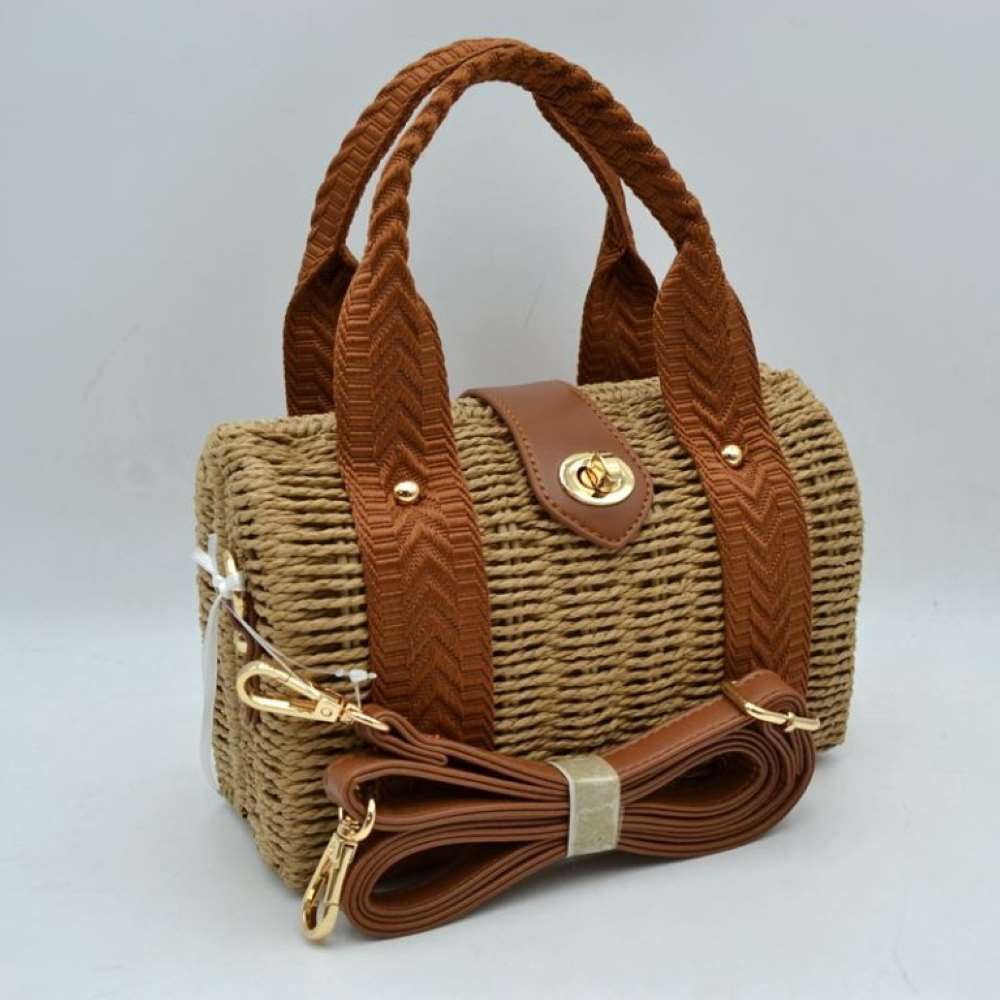 Khaki This structured barrel-shaped handbag features a textured, tightly woven body designed for unique everyday style. It is equipped with dual top handles featuring a distinctive chevron pattern, which are secured to the front and back panels with polished metallic studs. A central tab with a smooth texture extends over the top opening, fastening securely with a metallic turn-lock closure on the front.