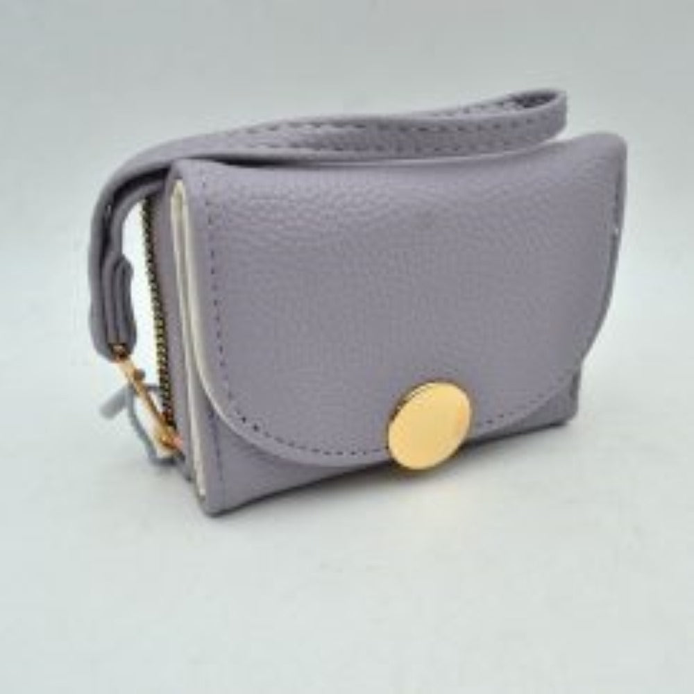 Lavender This compact everyday wallet features a pebbled, textured exterior designed for practical multi-compartment storage. It includes a secure, top zip-around section with metallic teeth alongside a front fold-over flap portion accented by a prominent round metallic button closure. For convenient carrying during daily errands, it comes equipped with a slim, matching wristlet strap attached to the side hardware.