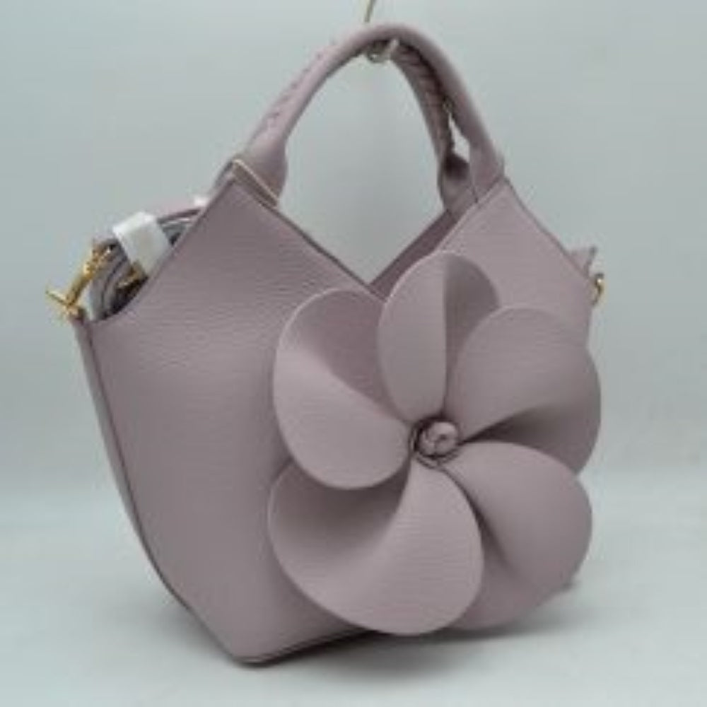 Lavender Make a whimsical yet sophisticated statement with this gorgeous winged satchel handbag, designed to bring an artistic and romantic flair to your accessory wardrobe. Crafted with a clean, structural silhouette and an elegant flared-wing shape, the front is beautifully adorned with a prominent, sculptural 3D five-petal flower applique that creates stunning dimension and immediate visual appeal. 