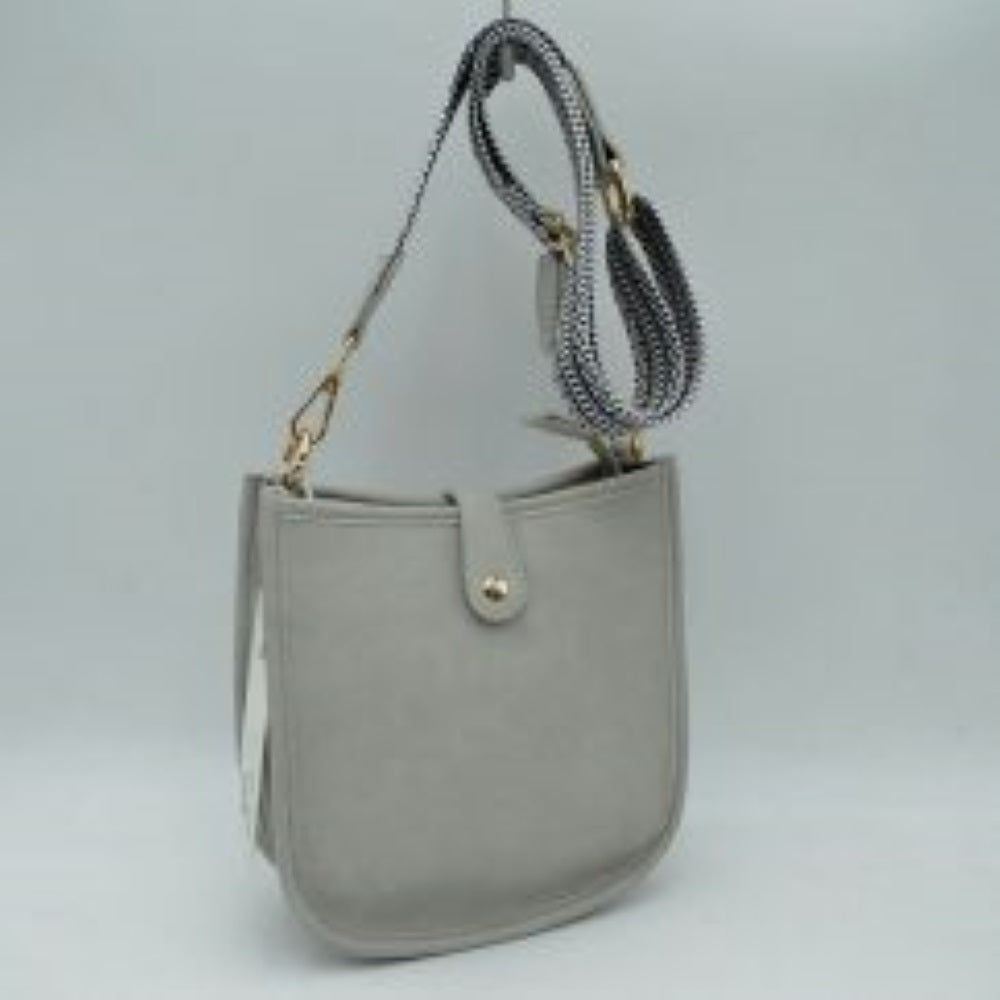 Light gray This stylish crossbody bag presents a clean, minimalist design with a smooth exterior finish and a distinct curved, U-shaped silhouette perfect for everyday use. It features an open top main compartment equipped with a small secure tab closure that fastens at the front with a metallic snap button. Adding a striking contrast, the bag is paired with a thick, adjustable fabric strap showcasing a bold geometric pattern