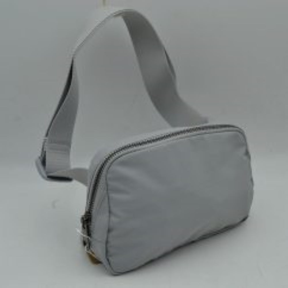 Light5 This minimalist bag features a smooth, clean design ideal for versatile everyday use. The main storage compartment is secured by a curved top zipper with dual pulls for easy access to essentials. A wide, adjustable strap extends from the sides, complete with a matching slider to easily customize the fit for comfortable carrying.