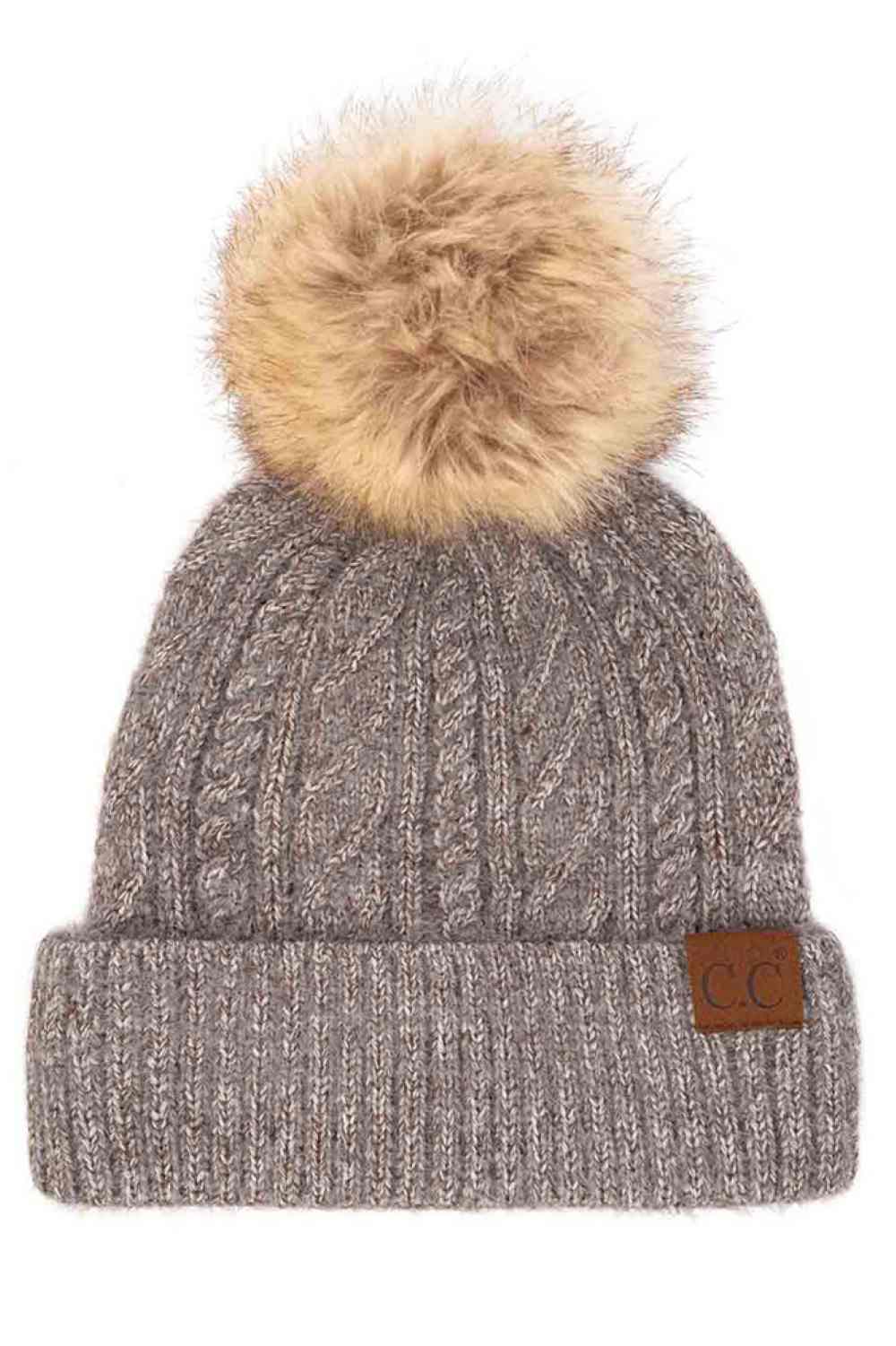 Grey The C.C Soft Cuff Beanie in Mixed Cable Pattern with Faux Fur Pom features a stylish blend of cable-knit textures topped with a plush faux fur pom for a chic winter look. Made from soft, stretchy fabric with a cozy cuff, it provides warmth, comfort, and a snug fit for cold-weather wear.